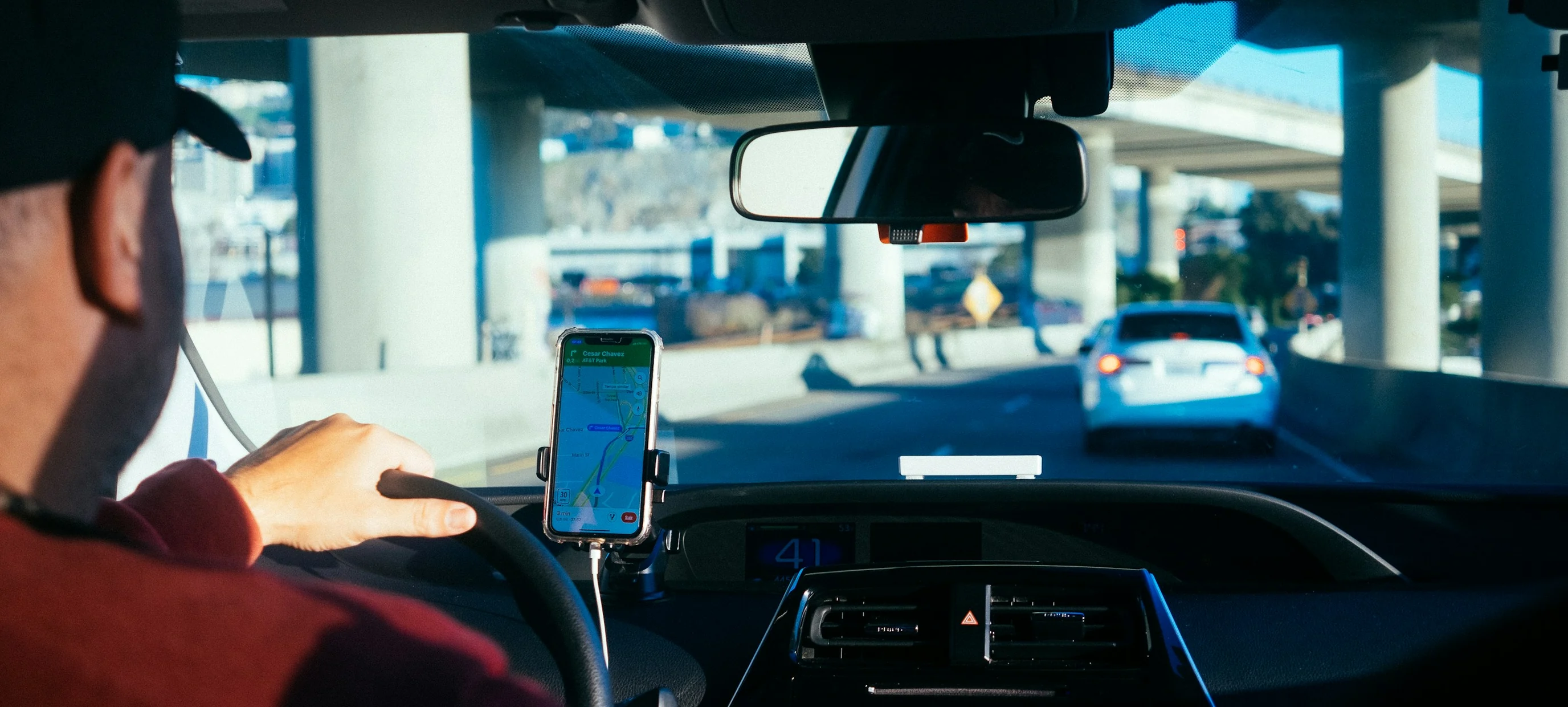 A driver at the wheel with a phone mounted on the dashboard